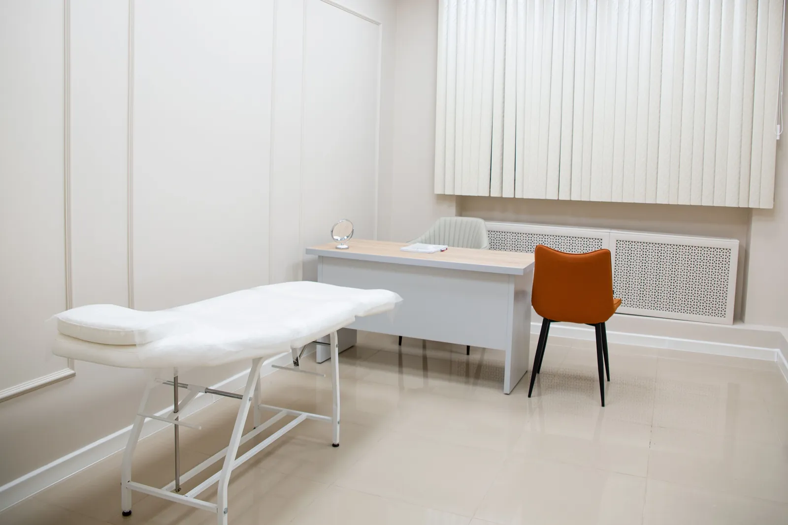 Bright exam room with a treatment bed and desk, shown to illustrate a visit with Dr. Jenna Patel, D.C.
