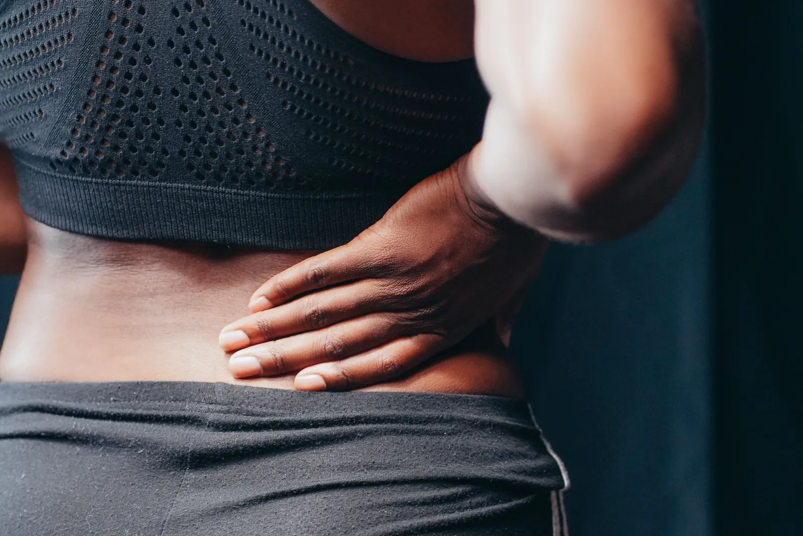 Person with back pain pressing both hands to the lower back
