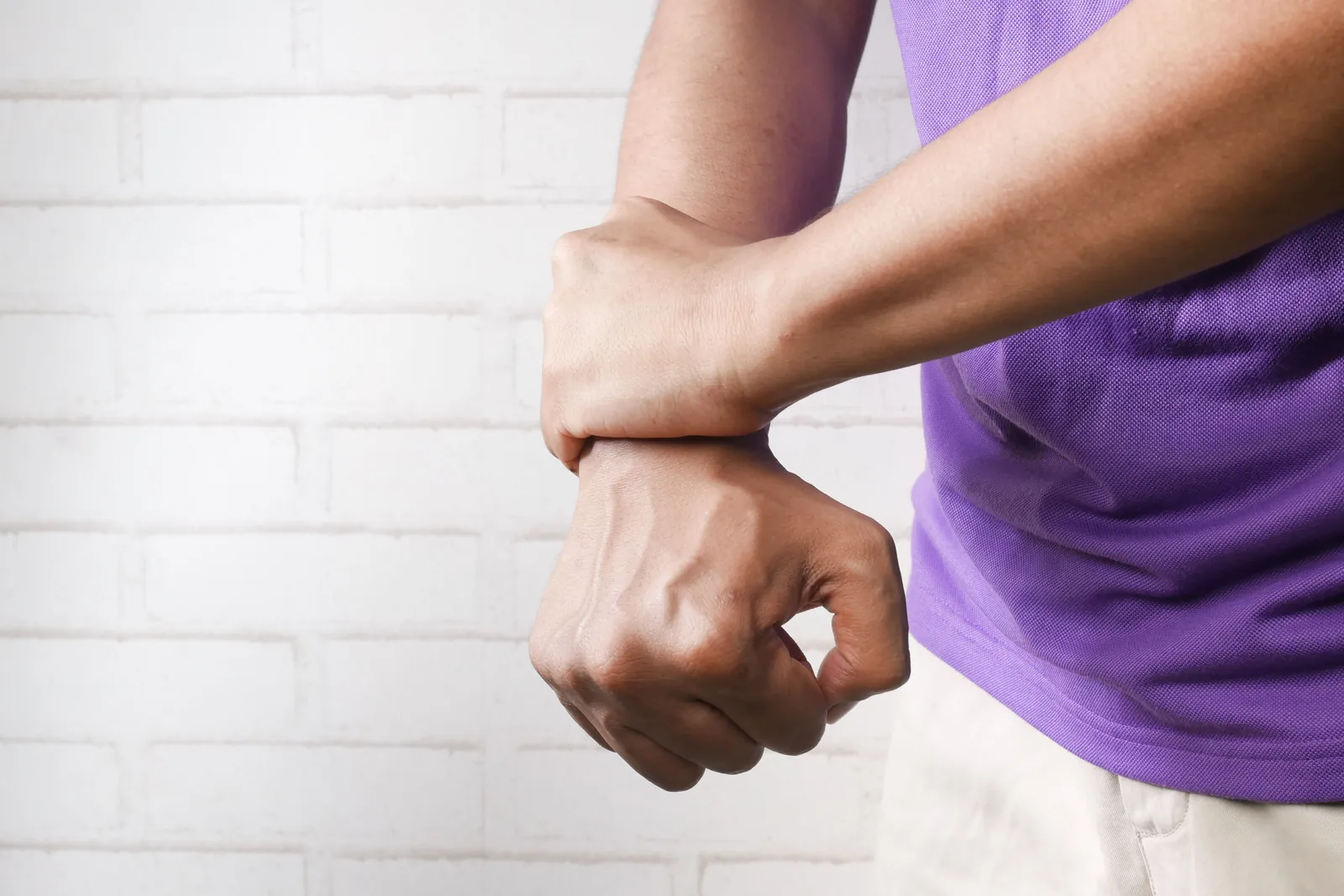 Person holding one wrist with the other hand, where carpal tunnel symptoms are often felt
