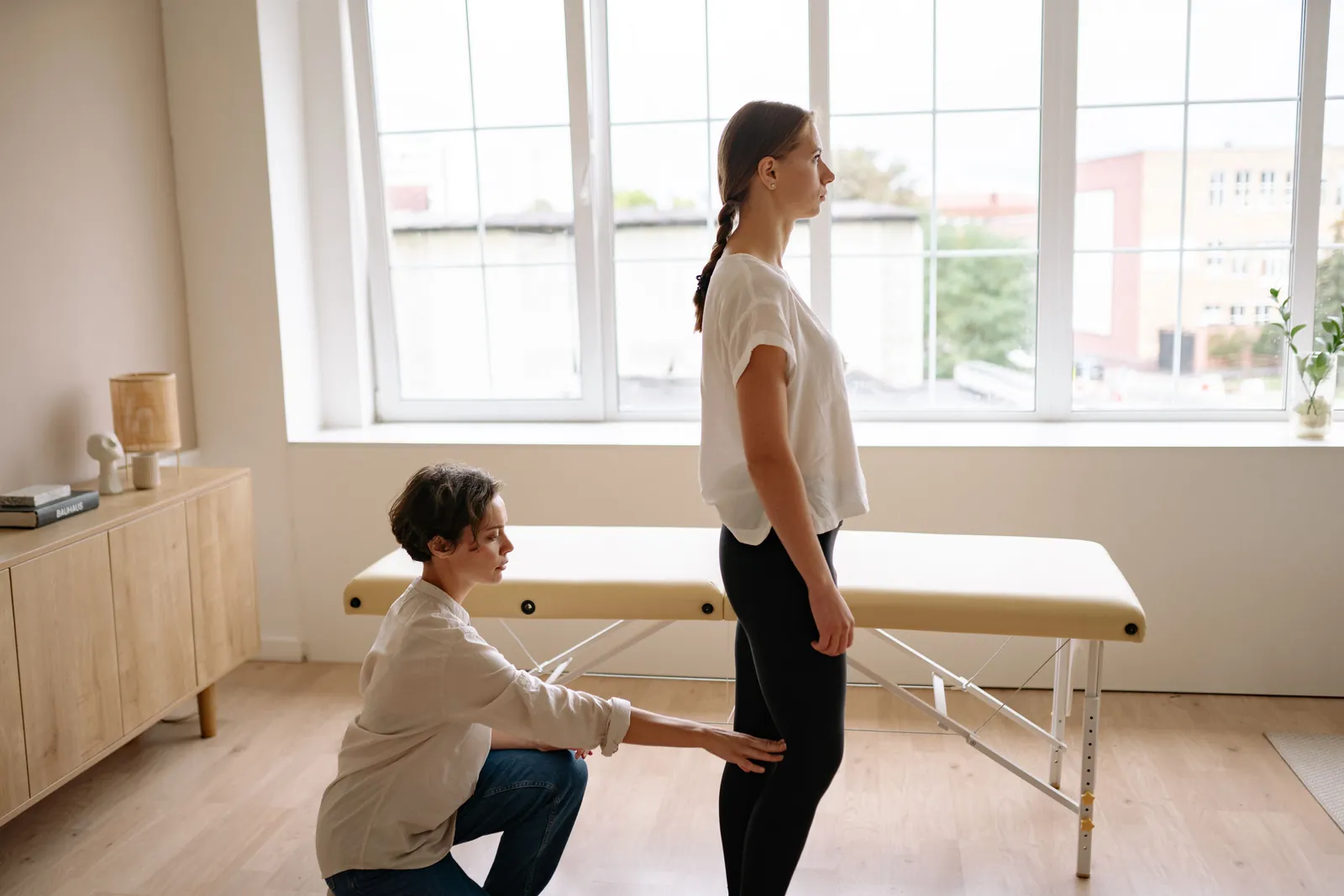 Practitioner checking a standing woman's posture, one step of a first chiropractic visit
