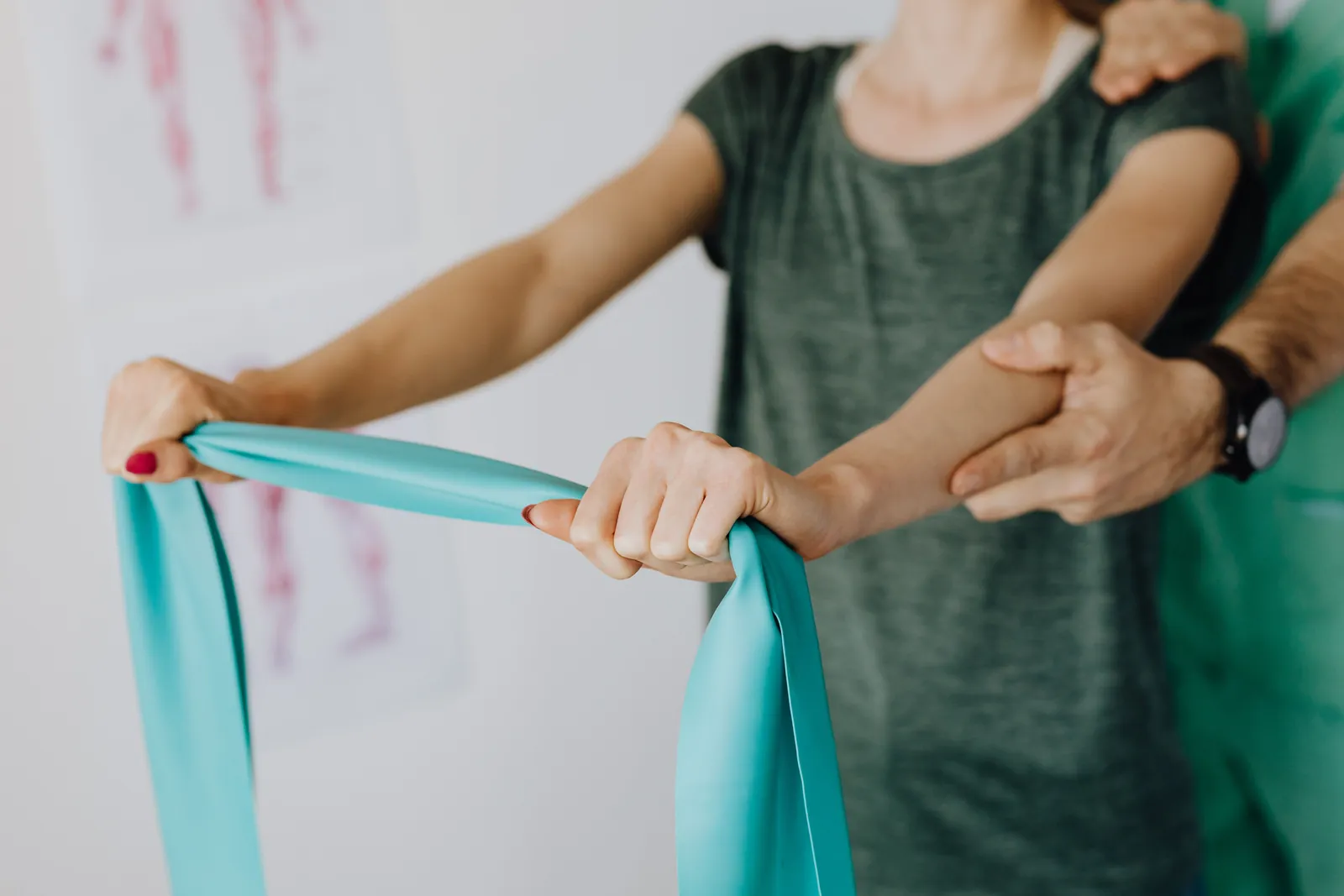 Woman stretching a resistance band during a functional exercise session while a practitioner supports her arm