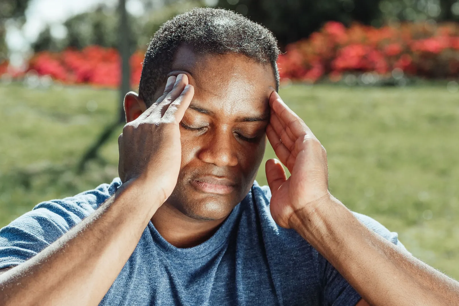 Man pressing his fingertips to his temples during a headache, a common reason to look for migraine relief