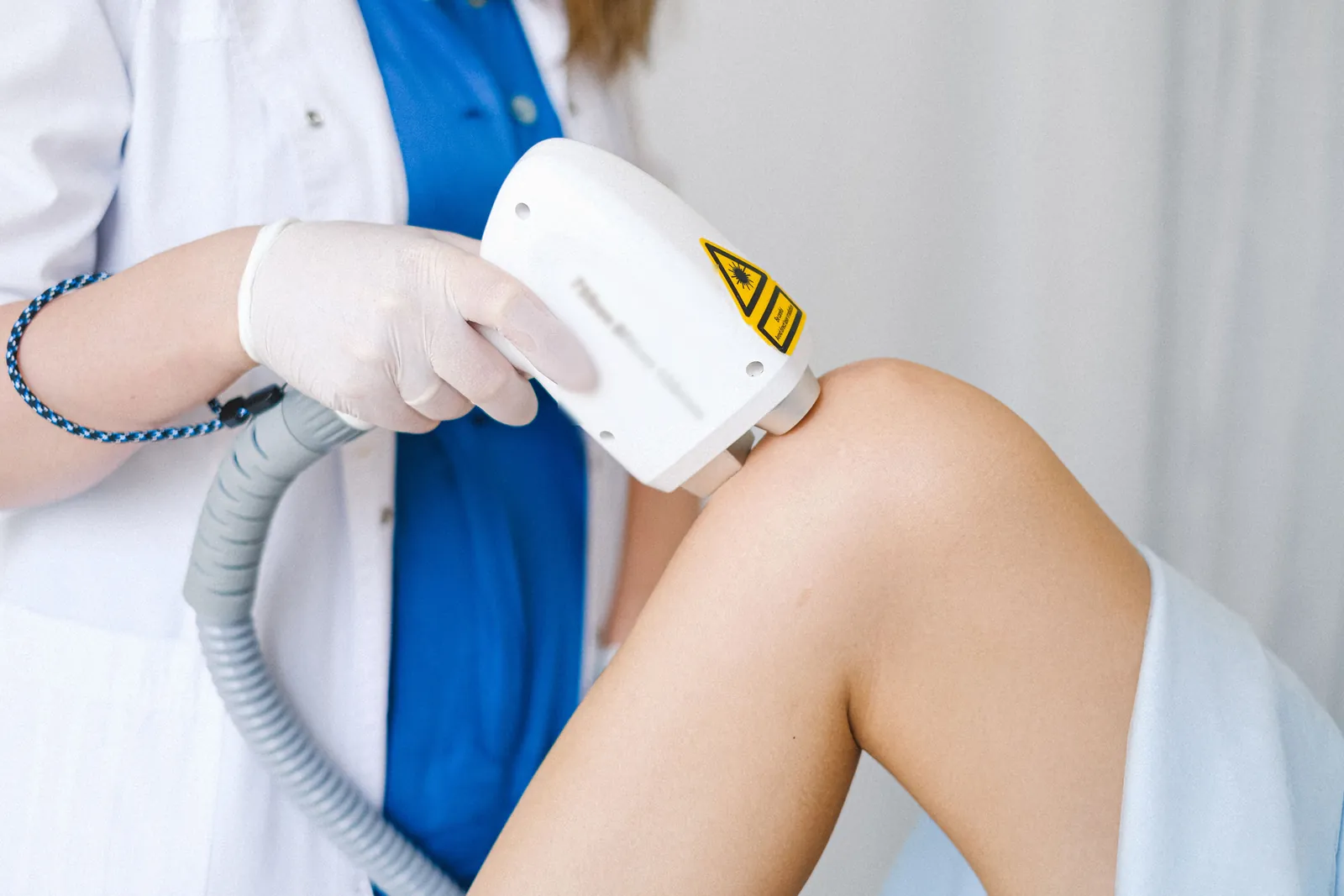 Handheld laser device held against a person's knee during laser therapy