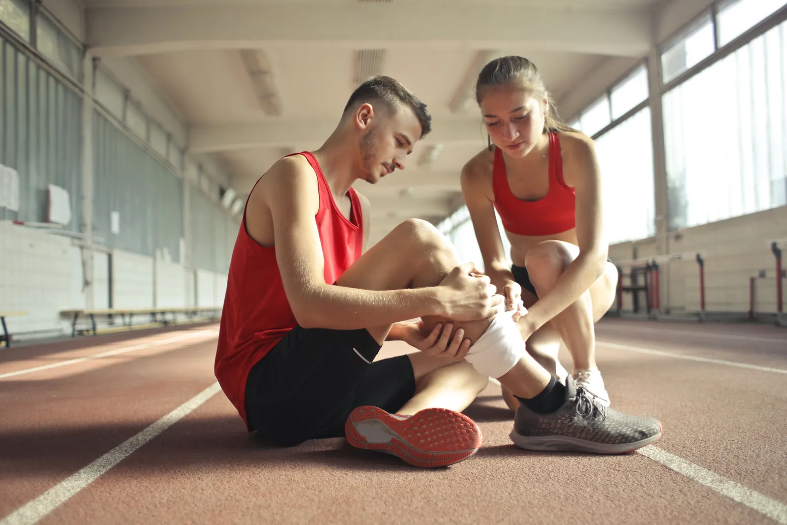 Athlete on an indoor track having his ankle wrapped after a sports injury
