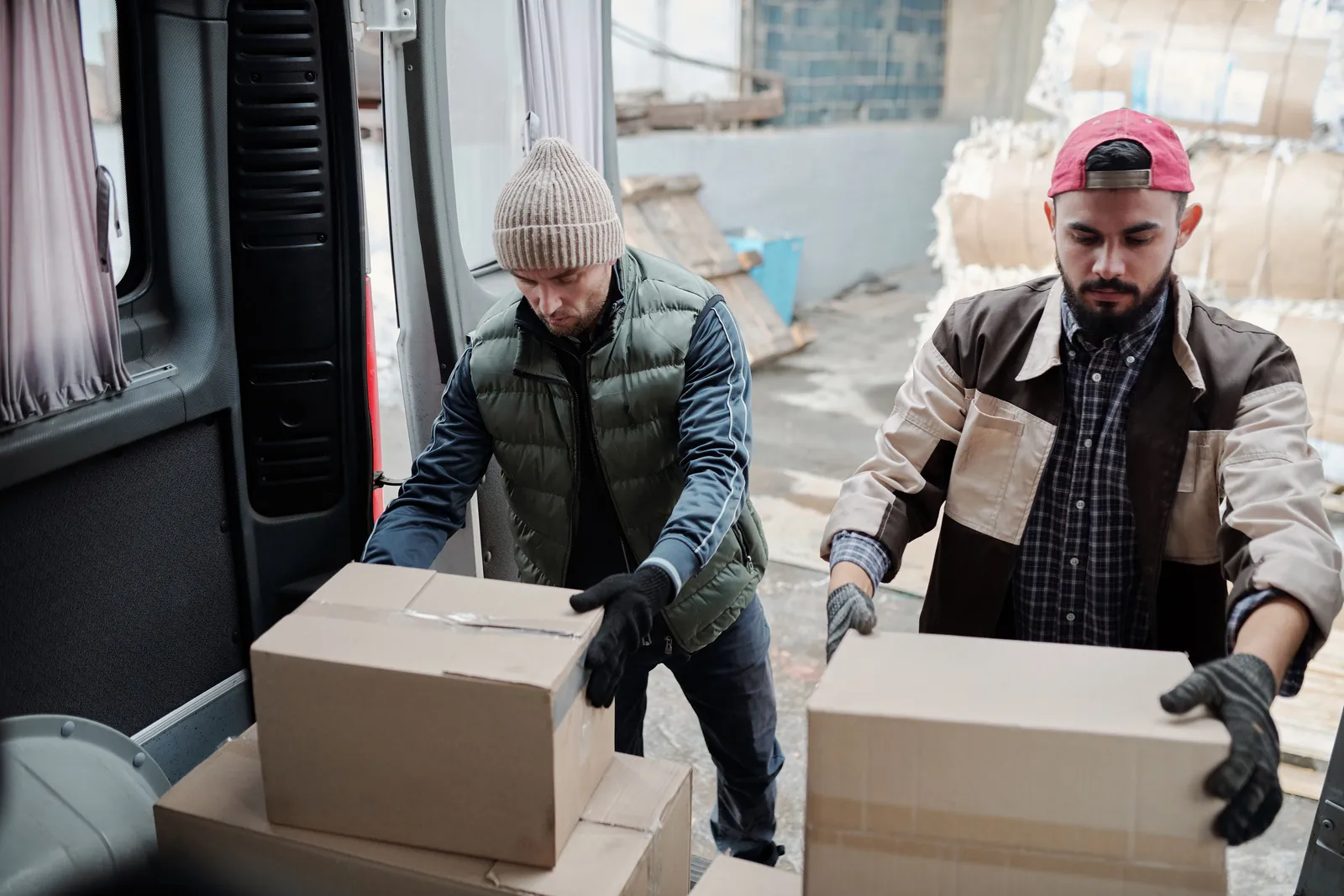 Two workers lifting boxes out of a van, a common cause of workplace injury