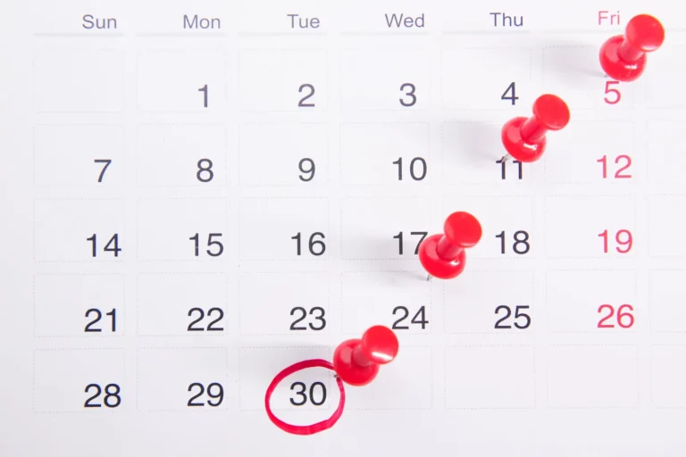Calendar page with red push pins marking dates, a simple way to plan spinal decompression sessions