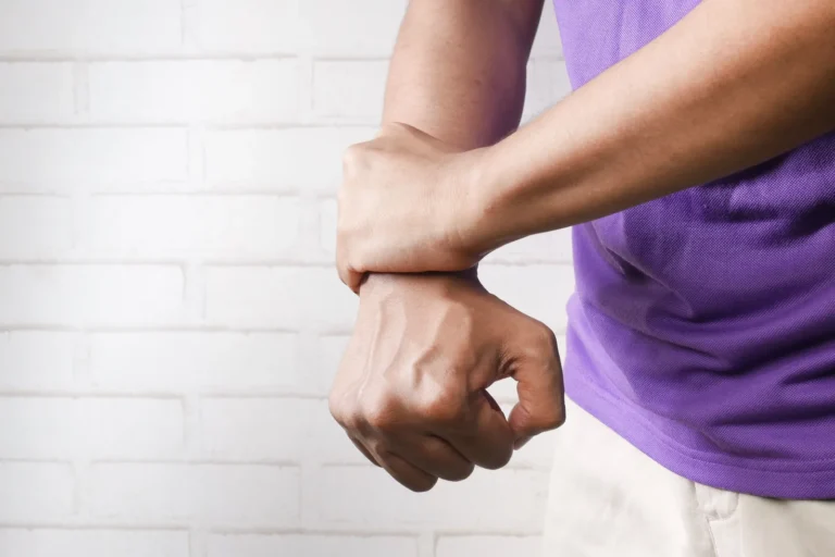 Person holding one wrist with the other hand, since hand tingling can come from a pinched nerve in the neck or from the wrist