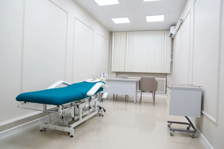 Empty treatment room with a teal treatment table and desk, with no spinal decompression or traction equipment in view