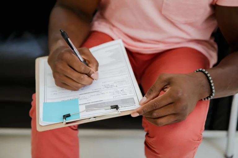 Person filling out a form on a clipboard, like an insurance form for spinal decompression care